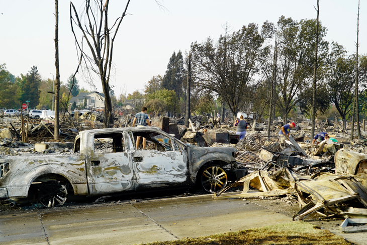 a photo of the damage from the Tubbs Fire including a burned out white pickup truck and debris from demolished homes