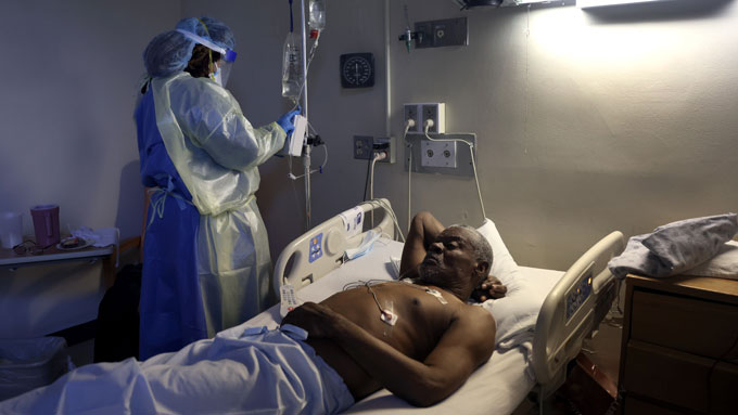 Curtis Jones lies in a hospital bed and receives a dose os remdesivir