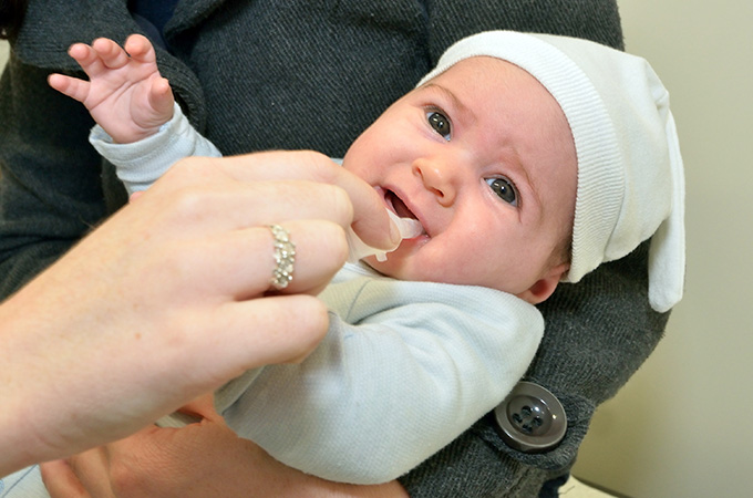 A bit of medicine is being squirted into the mouth of a baby.