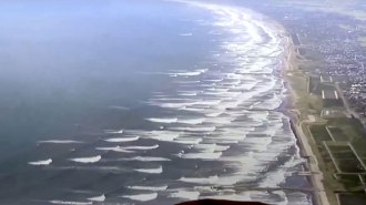 waves are shown from above moving towards a coastline